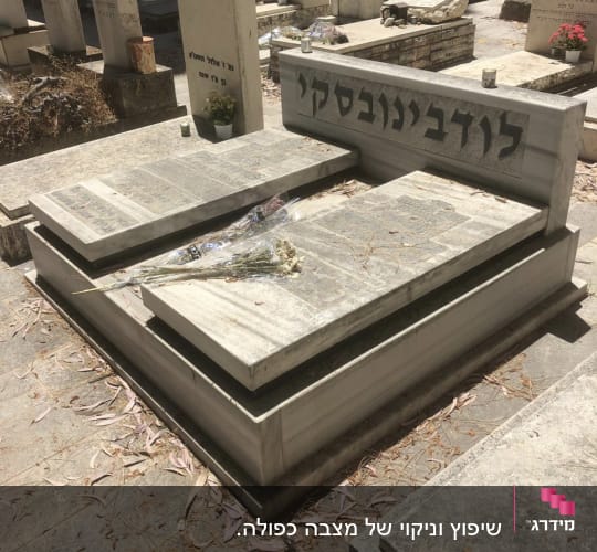 קבר עם מצבה ושם חקוק עליה, פרחים מונחים על הקבר